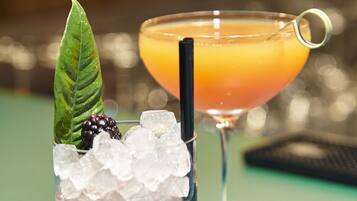 Two drinks on a table, one with ice and a blackberry, and the other with a straw.