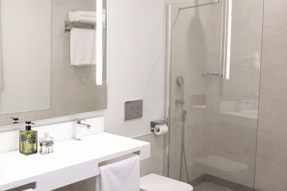 Une salle de bain moderne avec un meuble-lavabo blanc, une cabine de douche en verre et un grand miroir.