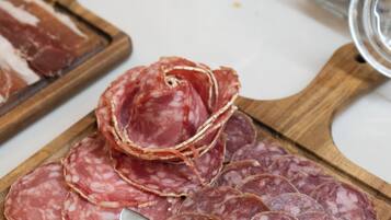 A wooden cutting board with sliced salami and a knife.