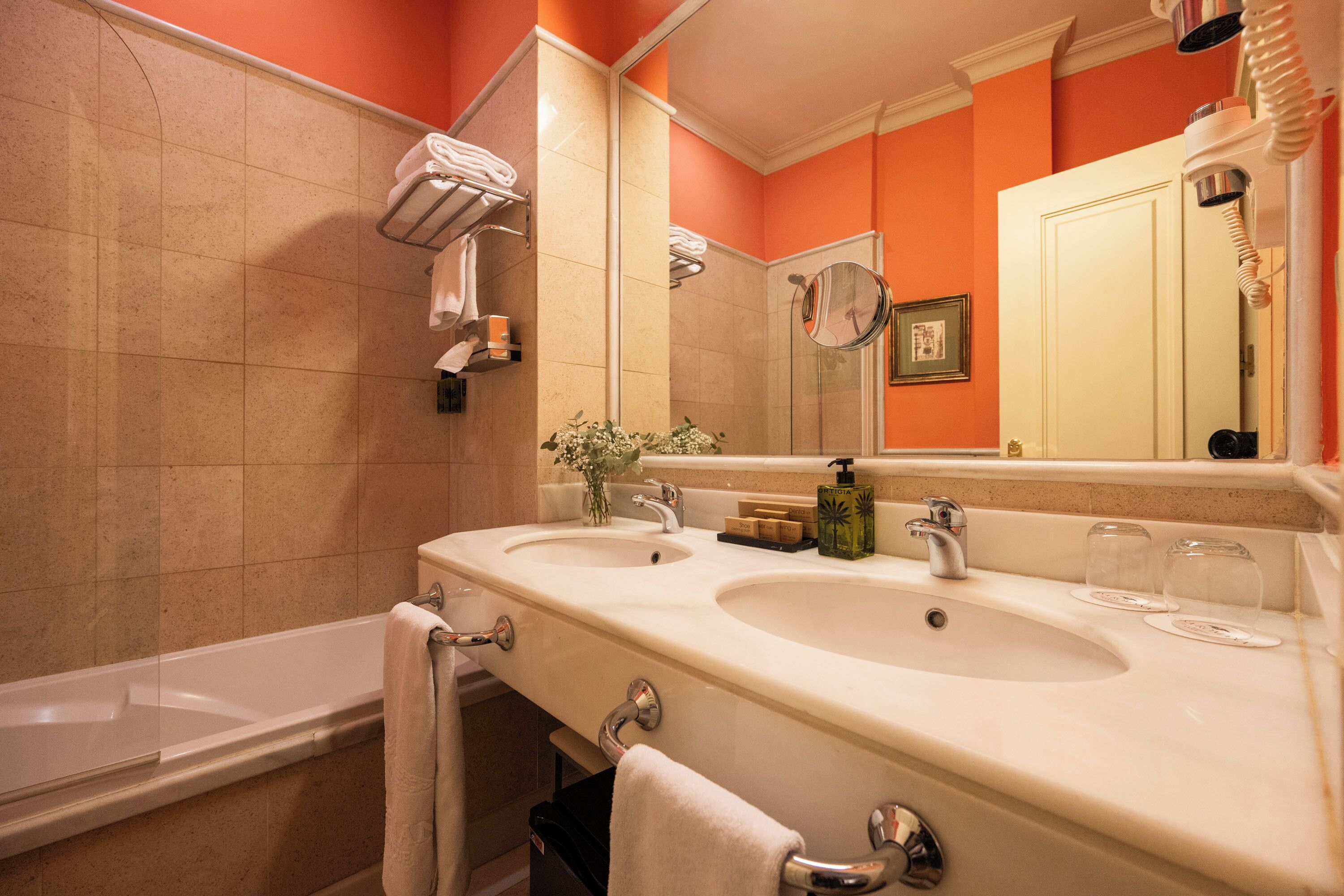 A bathroom with two sinks, a bathtub, and a large mirror.