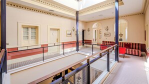 Un vaste atrium doté d’un haut plafond, d’un escalier central et d’un espace détente avec des fauteuils rouges.