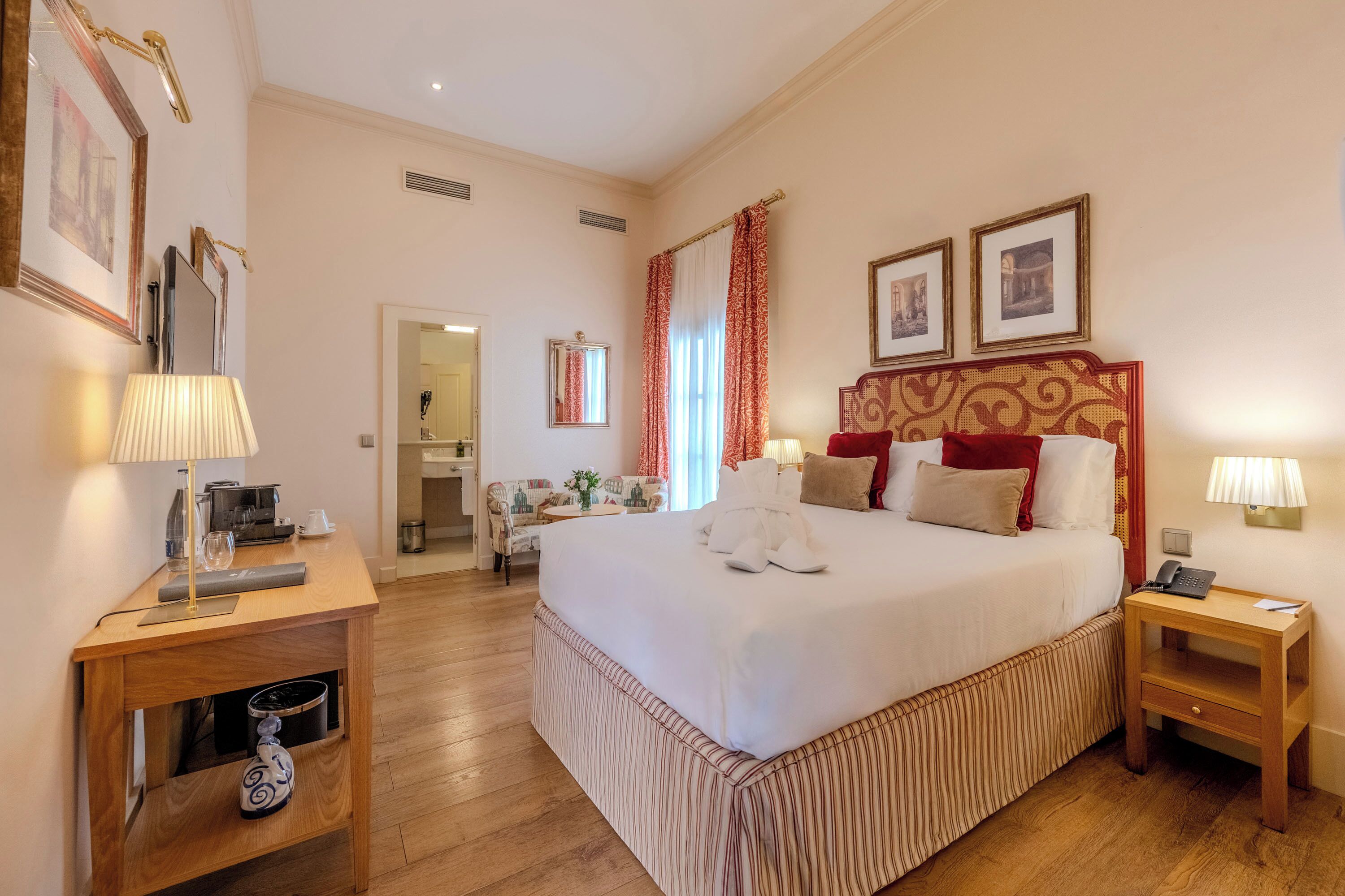 Una habitación de hotel con una cama grande, mesitas de noche, un escritorio y una silla.