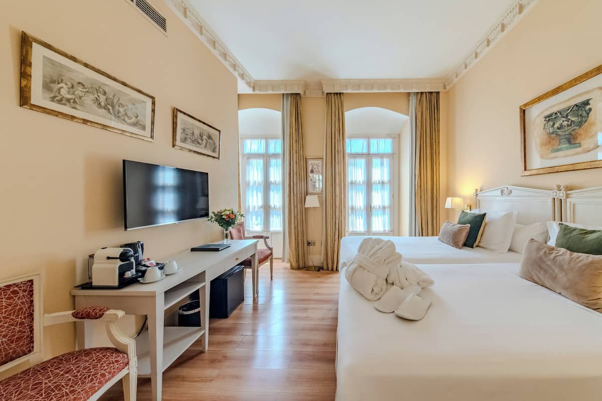 Een hotelkamer met een bed, een bureau, een televisie en kunstwerken aan de wanden.