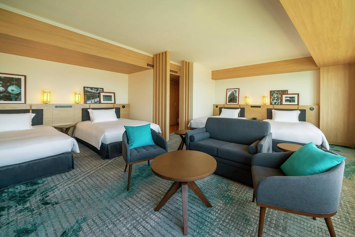 Une chambre d’hôtel avec deux lits, un canapé, une petite table et une chaise.