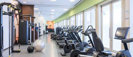 Un gimnasio con cintas de correr, elípticas y pesas sueltas.