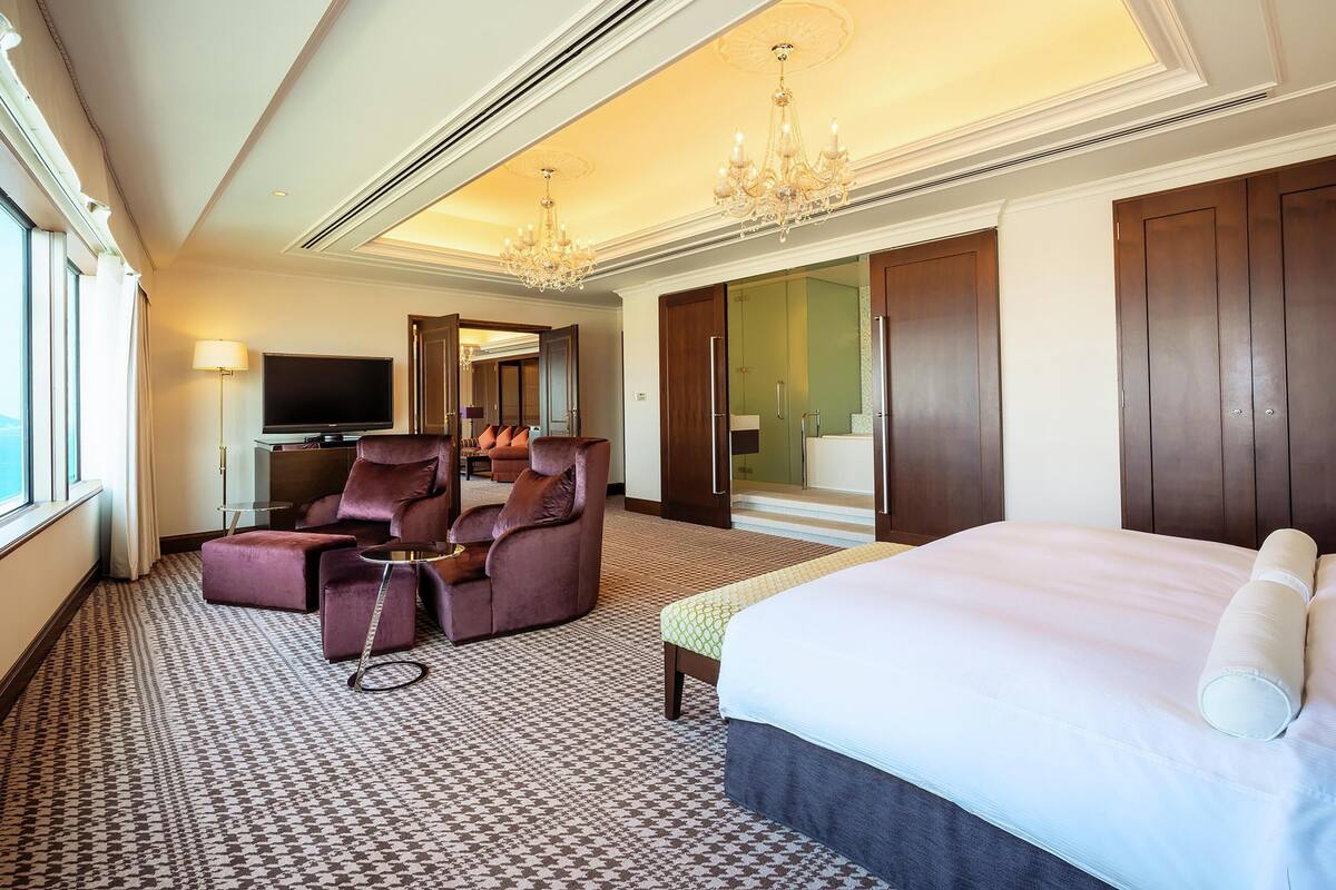 Une chambre d’hôtel avec un grand lit, un canapé, une télévision et un miroir.