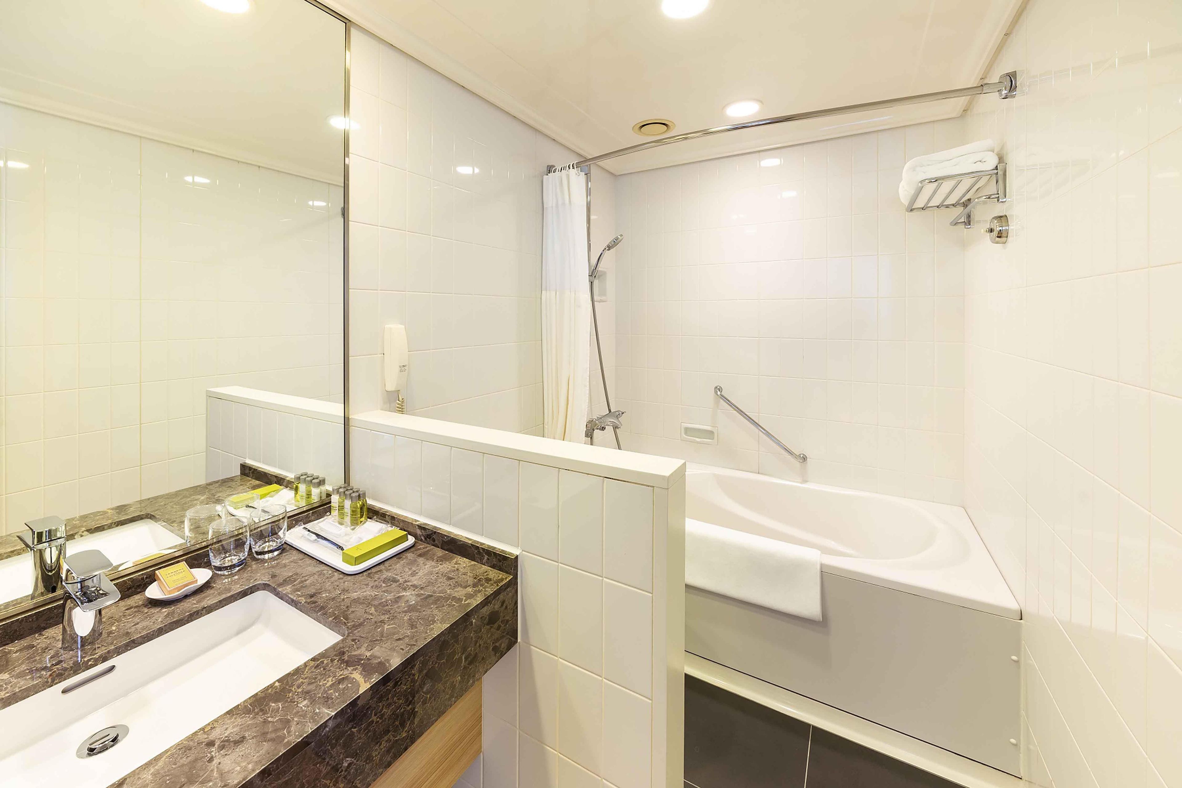 Ein modernes Badezimmer mit Marmorwaschbecken, einer Badewanne und einer Dusche.