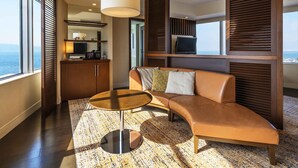 A modern living room with a sofa, a coffee table, a television, and a view of the sea.