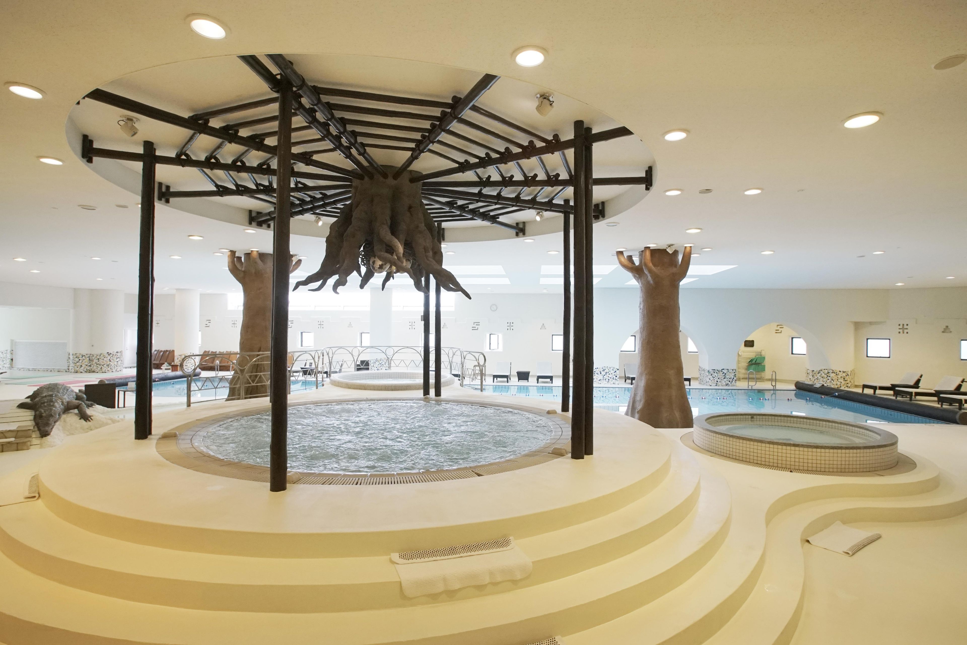 A pool area with a central hot tub, surrounded by steps and lounge chairs.