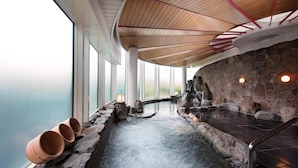 Un área de spa con pared de piedra, techo de madera y vistas al agua.