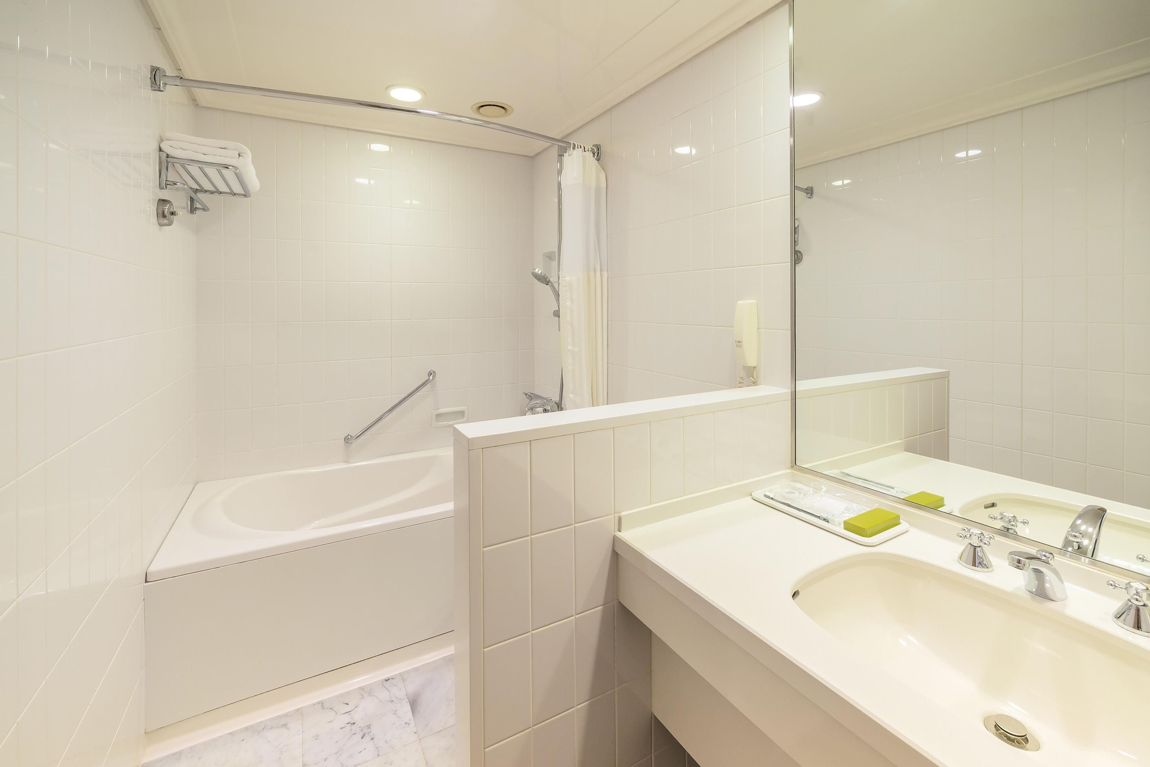 A modern bathroom with a bathtub, shower, and a large mirror.