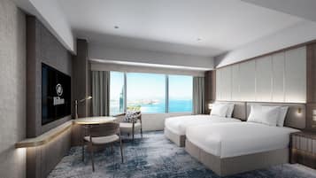 A hotel room with a large bed, a desk, a chair, a TV, and a view of the city.