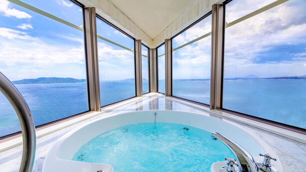 Un jacuzzi con vistas despejadas al mar a través de grandes ventanales.