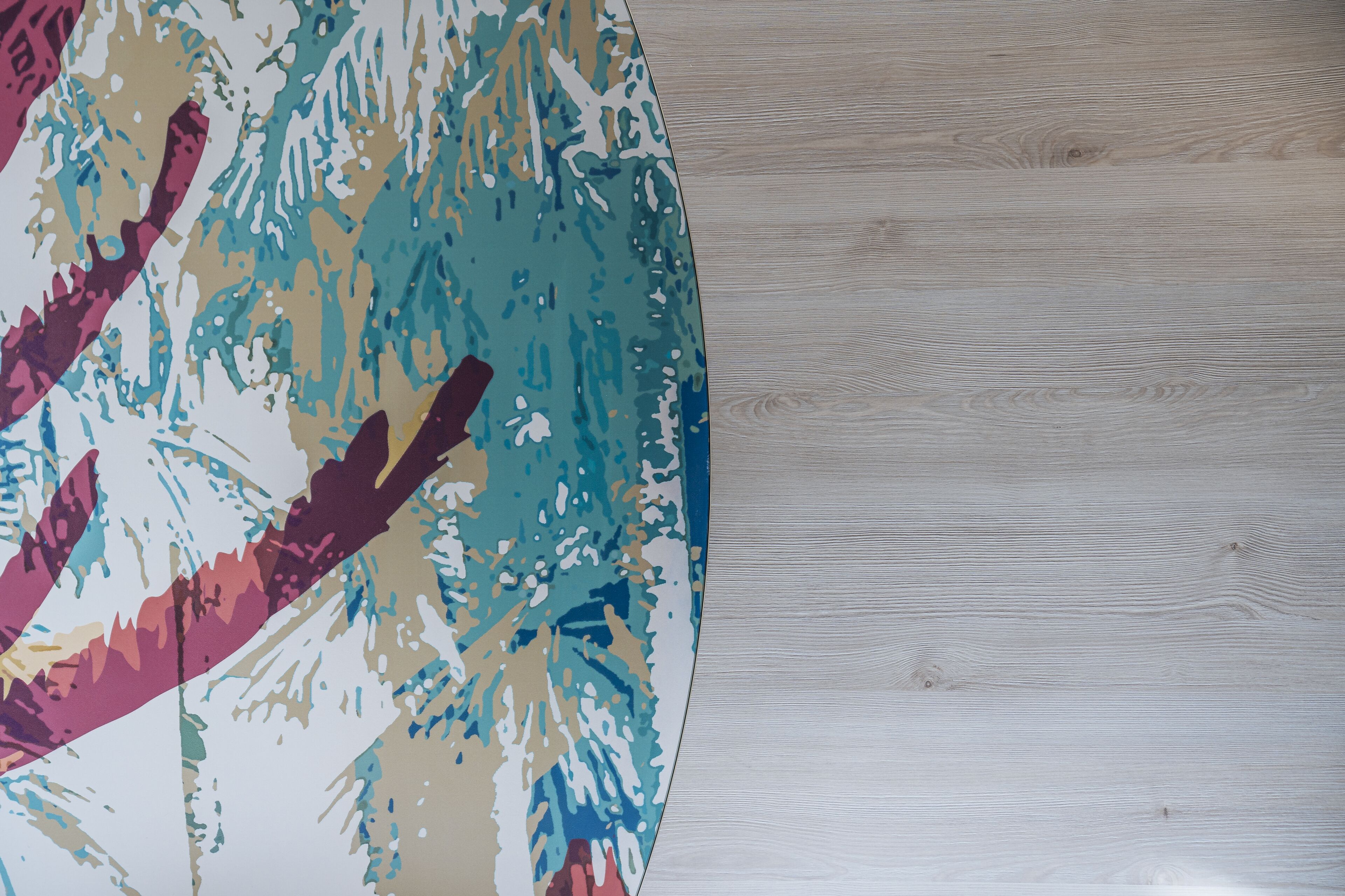 Un mur orné d’une fresque abstraite aux couleurs vives et d’un panneau en bois sobre.