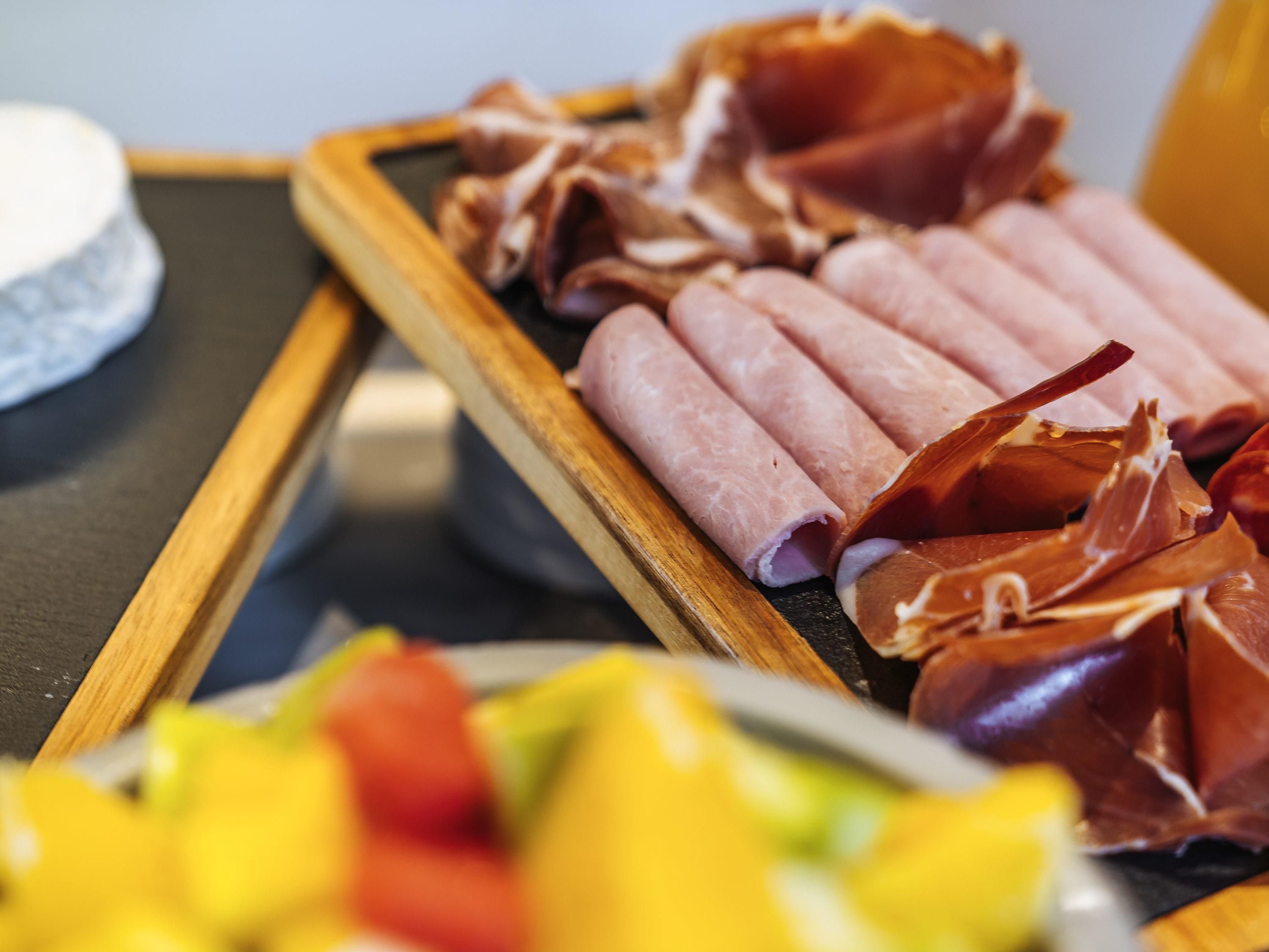 Una bandeja de madera con varios embutidos curados.