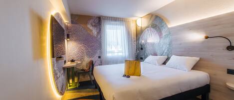 A modern hotel room with a large bed, a desk, and a chair.
