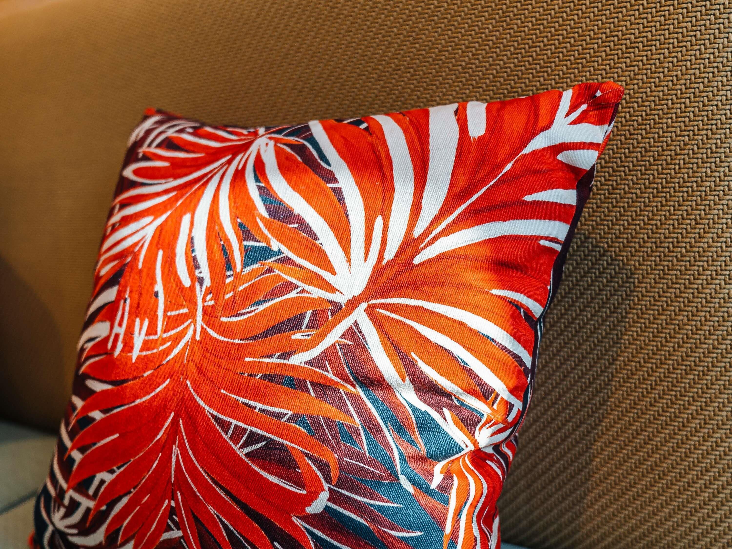A pillow with a leaf pattern on a textured sofa.