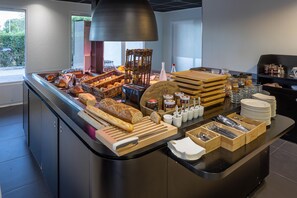 A breakfast buffet with various breads, pastries, and condiments. - Noemys Arles (Arles)