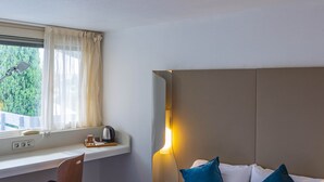 A hotel room with a bed, a desk, and a window. - Noemys Arles (Arles)