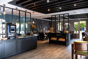 Una cafetería moderna con una isla central, zona de estar y una máquina de café.