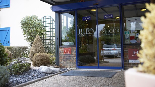 A restaurant entrance with a blue awning, glass doors, and a sign reading "BIEN SEJOUR VENUE WELCOME ENJOY YOUR STAY." - Kyriad - Beaune (Beaune)