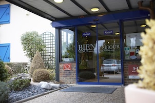 Entrada a un restaurante con toldo azul, puertas de cristal y un letrero que dice "BIEN SEJOUR VENUE WELCOME ENJOY YOUR STAY".