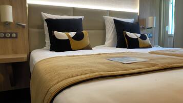 A hotel room with a large bed, two bedside tables, a nightstand, a lamp, and a window with curtains.