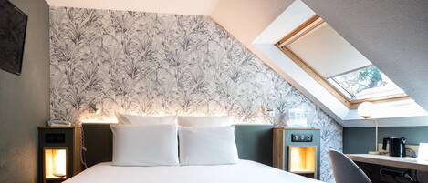 A bedroom with a bed, two bedside tables, a desk, and a skylight.