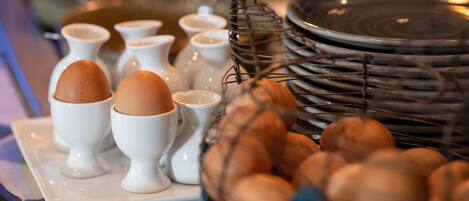 A breakfast buffet with various egg dishes and a wicker basket filled with eggs.