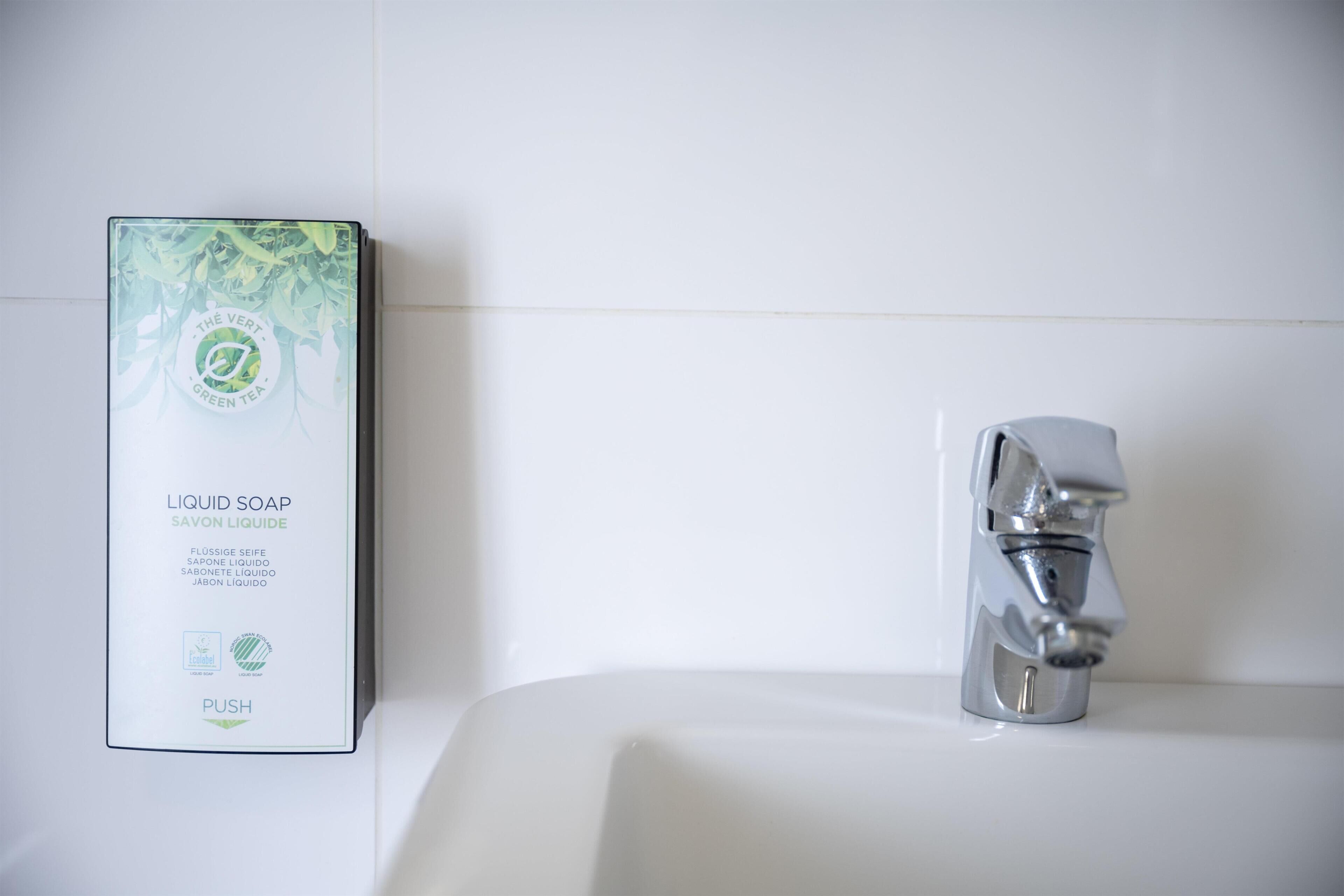 Un baño con un lavamanos blanco, un grifo cromado y una caja de jabón de té verde.