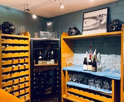 Un sótano de vinos con estanterías de madera llenas de botellas y copas.