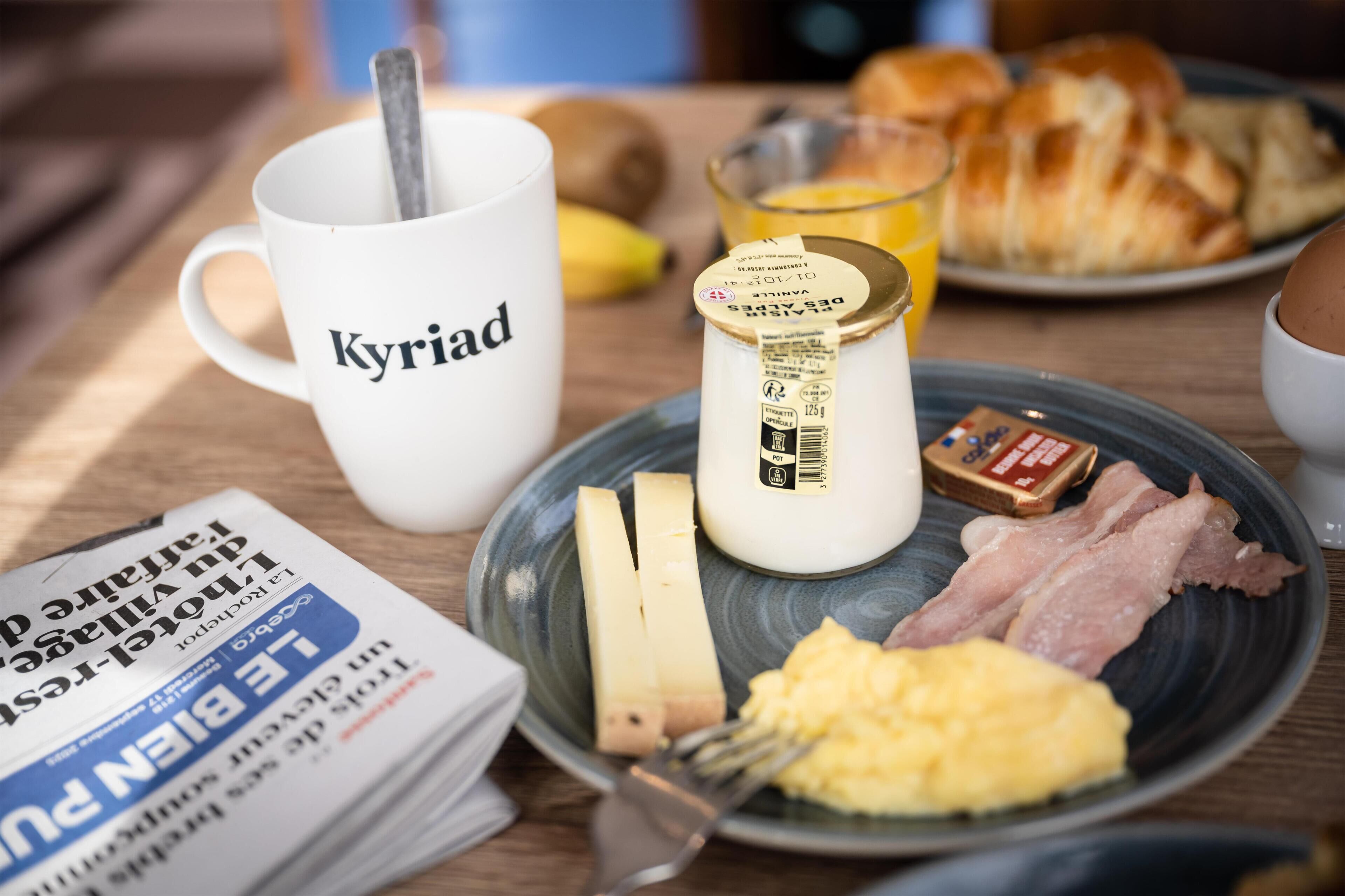 A breakfast table with a plate of eggs, bacon, cheese, and a glass of orange juice.