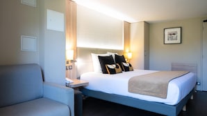 A hotel room with a bed, bedside table, lamp, and a chair. - Kyriad - Beaune (Beaune)