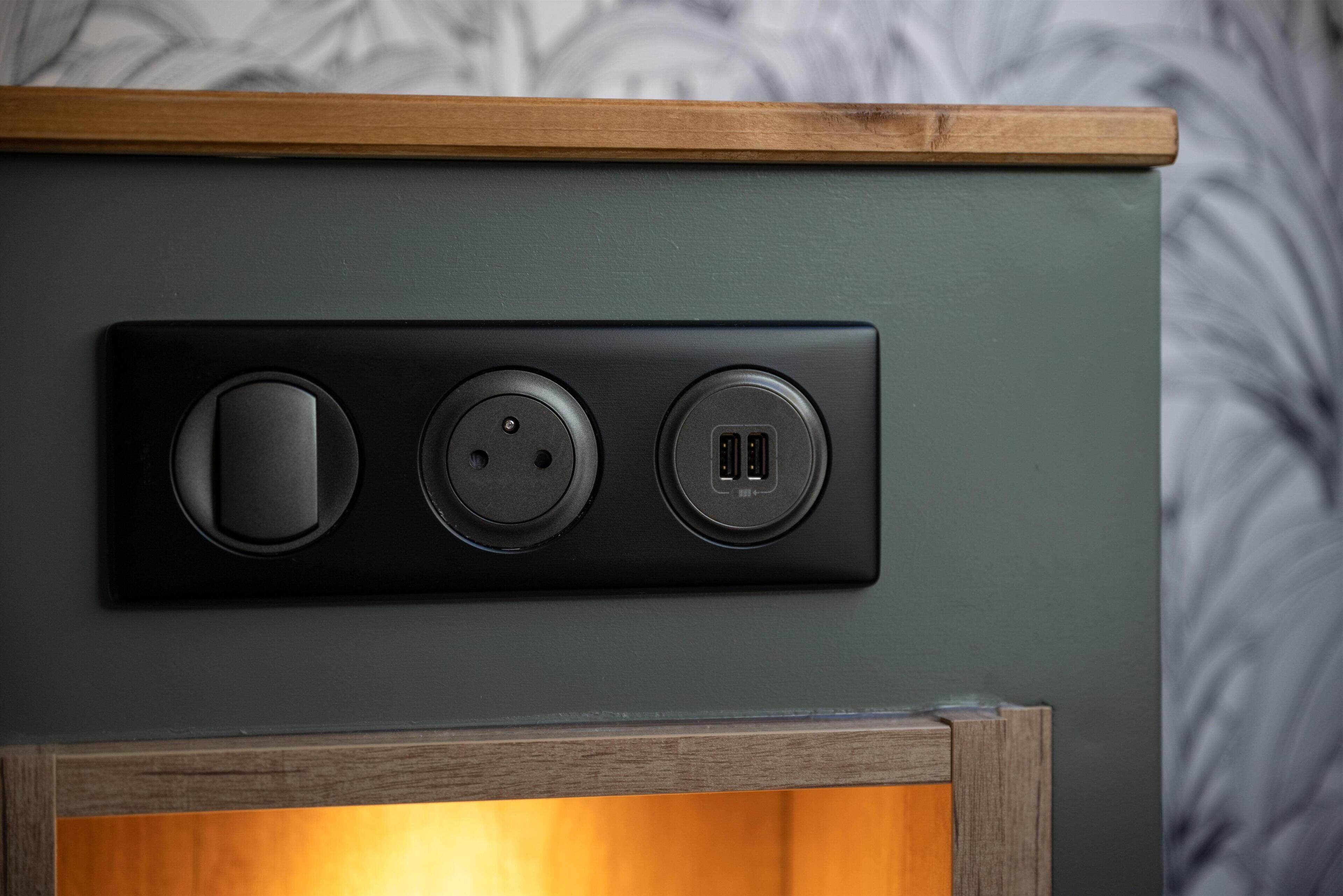 A wall-mounted electrical outlet with three sockets, a USB port, and a power button.