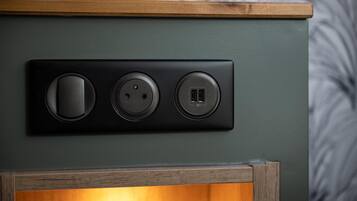 A wall-mounted electrical outlet with three sockets, a USB port, and a power button.