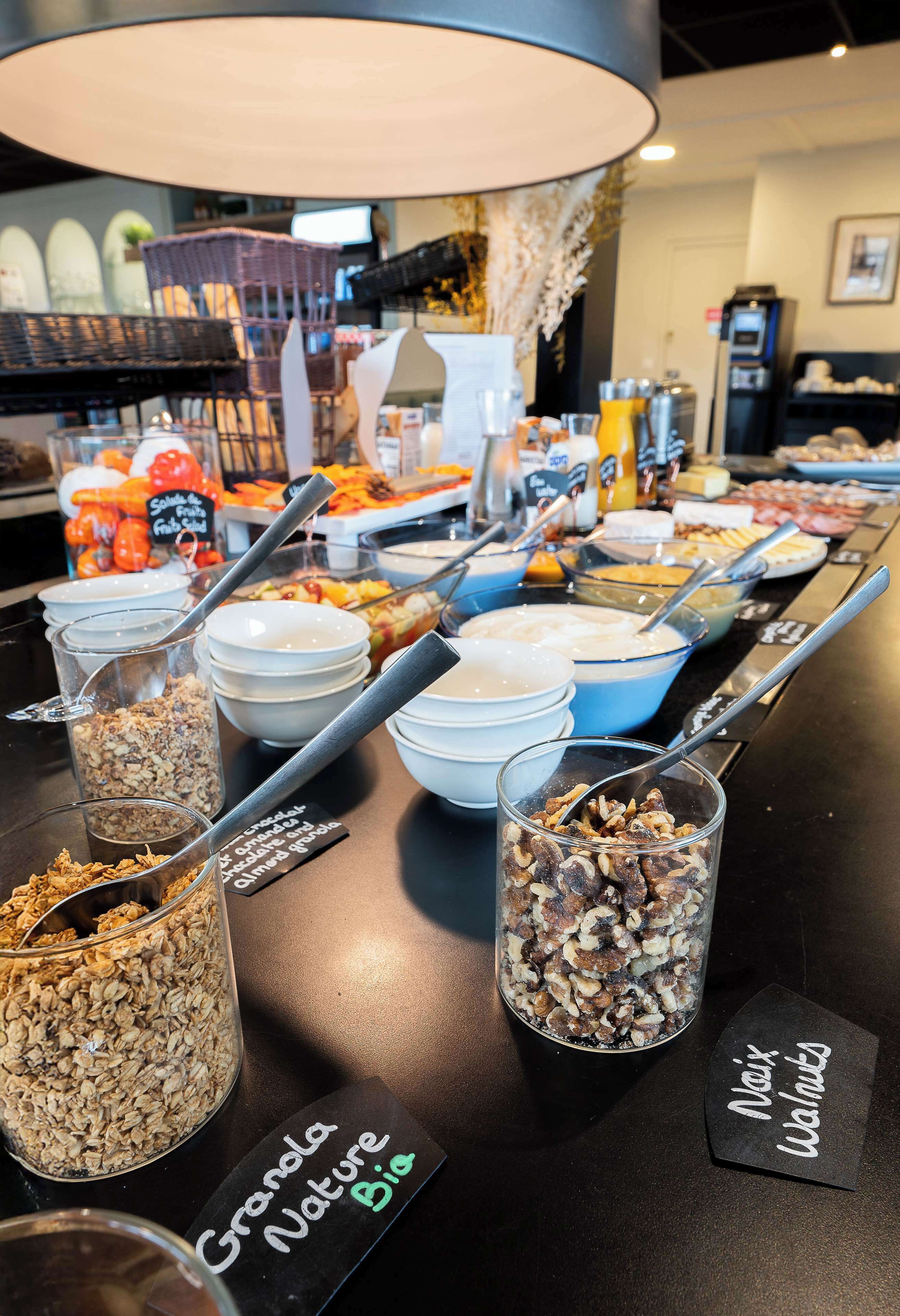 A buffet with various food options including granola, nuts, and fresh fruits.