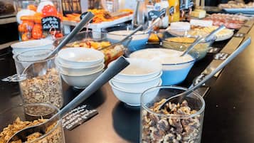 A buffet with various food options including granola, nuts, and fresh fruits.