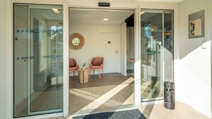 A modern interior with a glass door entrance, a small round table with chairs, and a decorative wall hanging. - Sure Hotel by Best Western Rochefort-Sur-Mer (Tonnay-Charente)