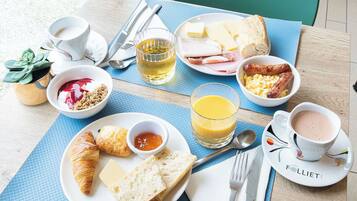 A breakfast table with plates of food, cups, and cutlery.