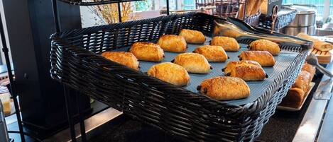 A buffet setup with bread and pastries.