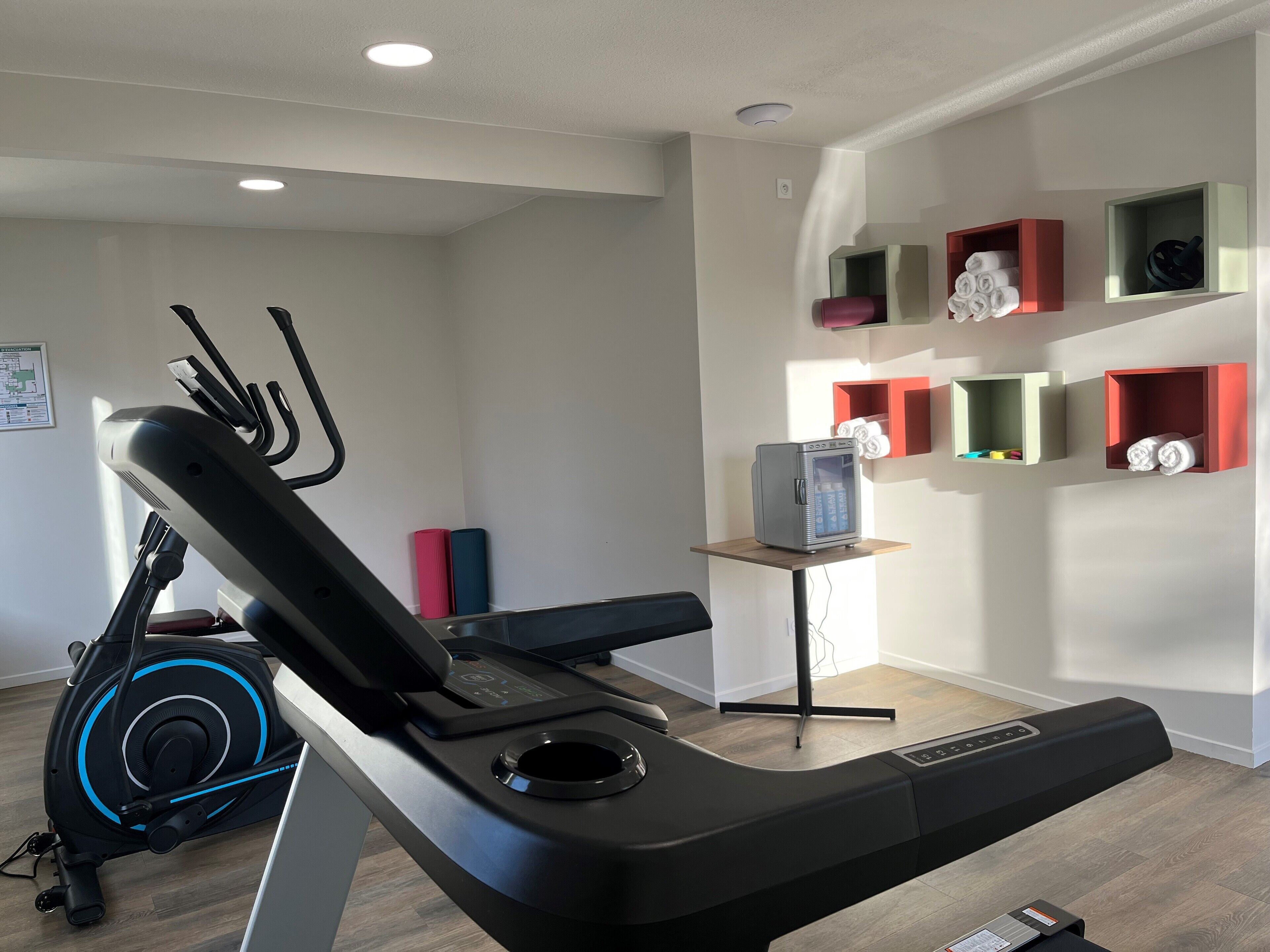 A modern home gym with a stationary bike, elliptical, and a treadmill.