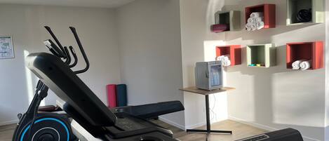 A modern home gym with a stationary bike, elliptical, and a treadmill.