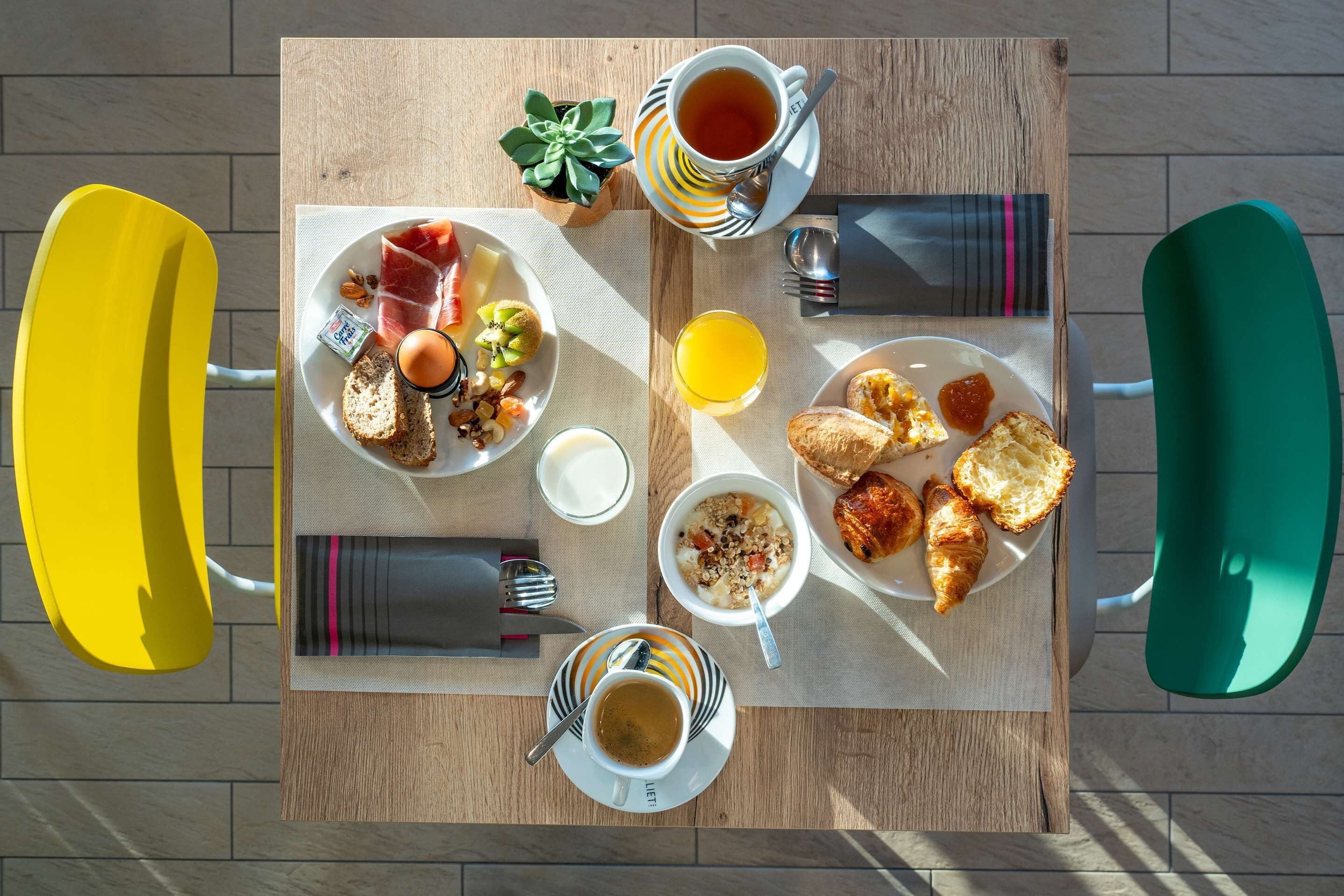 A breakfast table with various food items, a cup of tea, and a small plant.