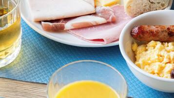A breakfast plate with ham, cheese, sausage, bread, and scrambled eggs.