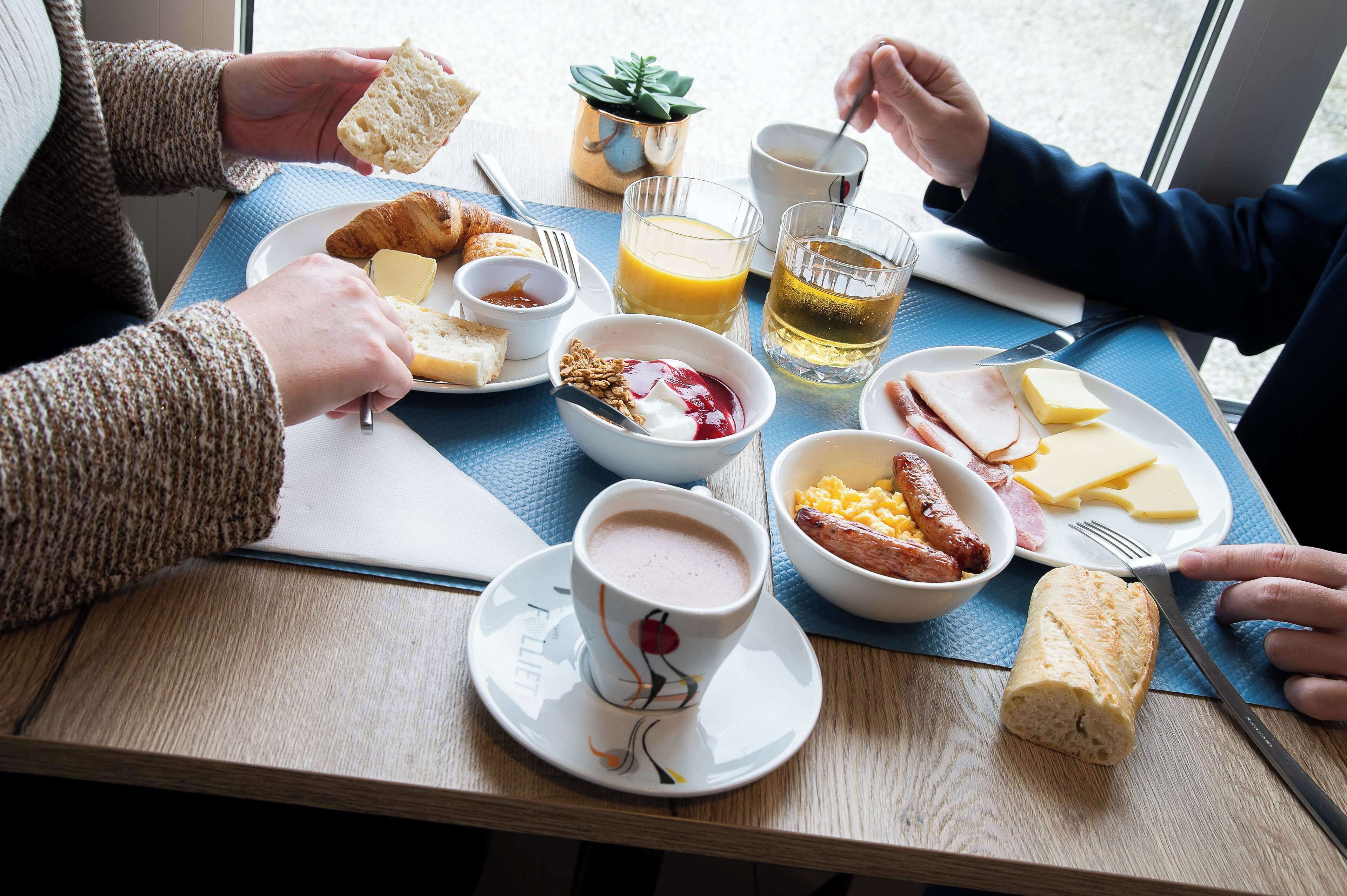 A breakfast setting with croissants, cheese, ham, and a croissant roll on a wooden table.