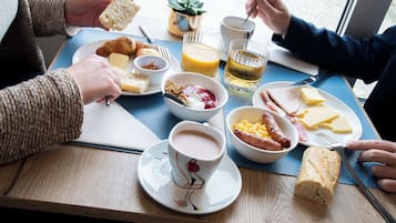 A breakfast setting with croissants, cheese, ham, and a croissant roll on a wooden table.