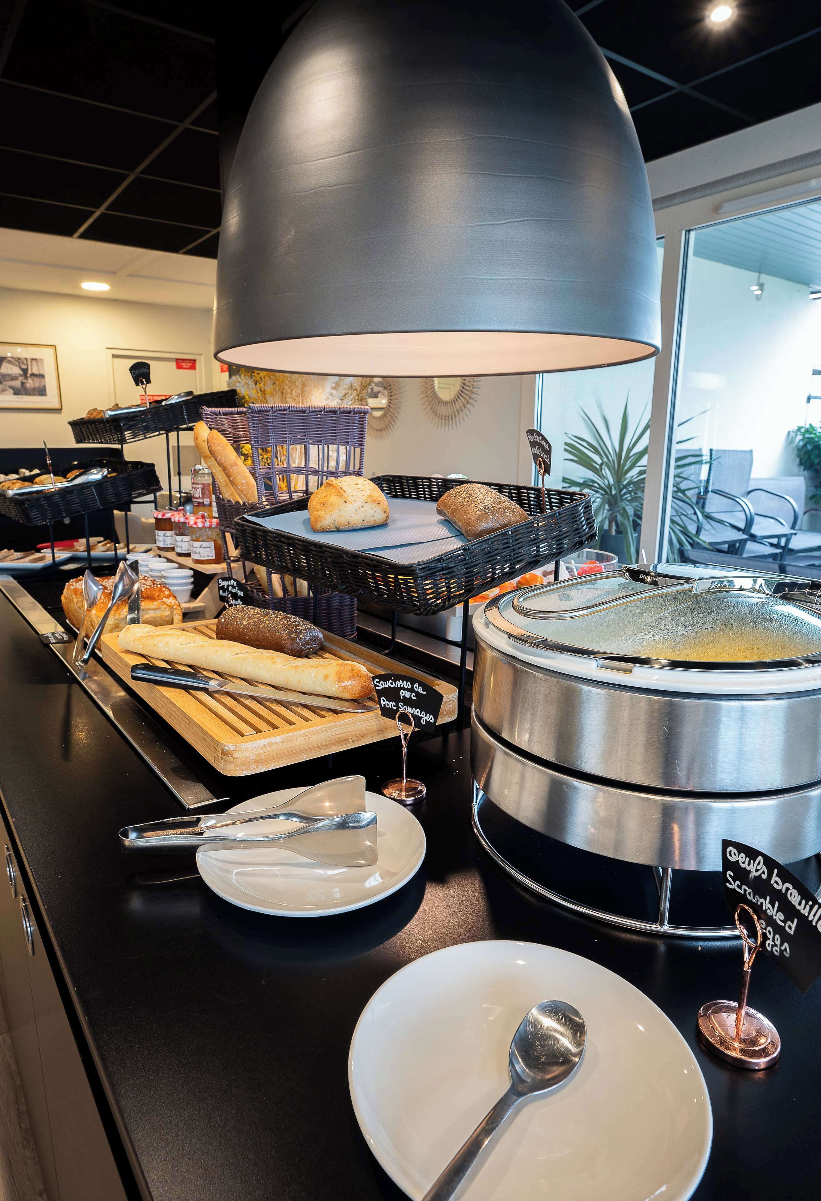Een buffetopstelling met diverse gerechten, een grote metalen pan en een hangende lamp.