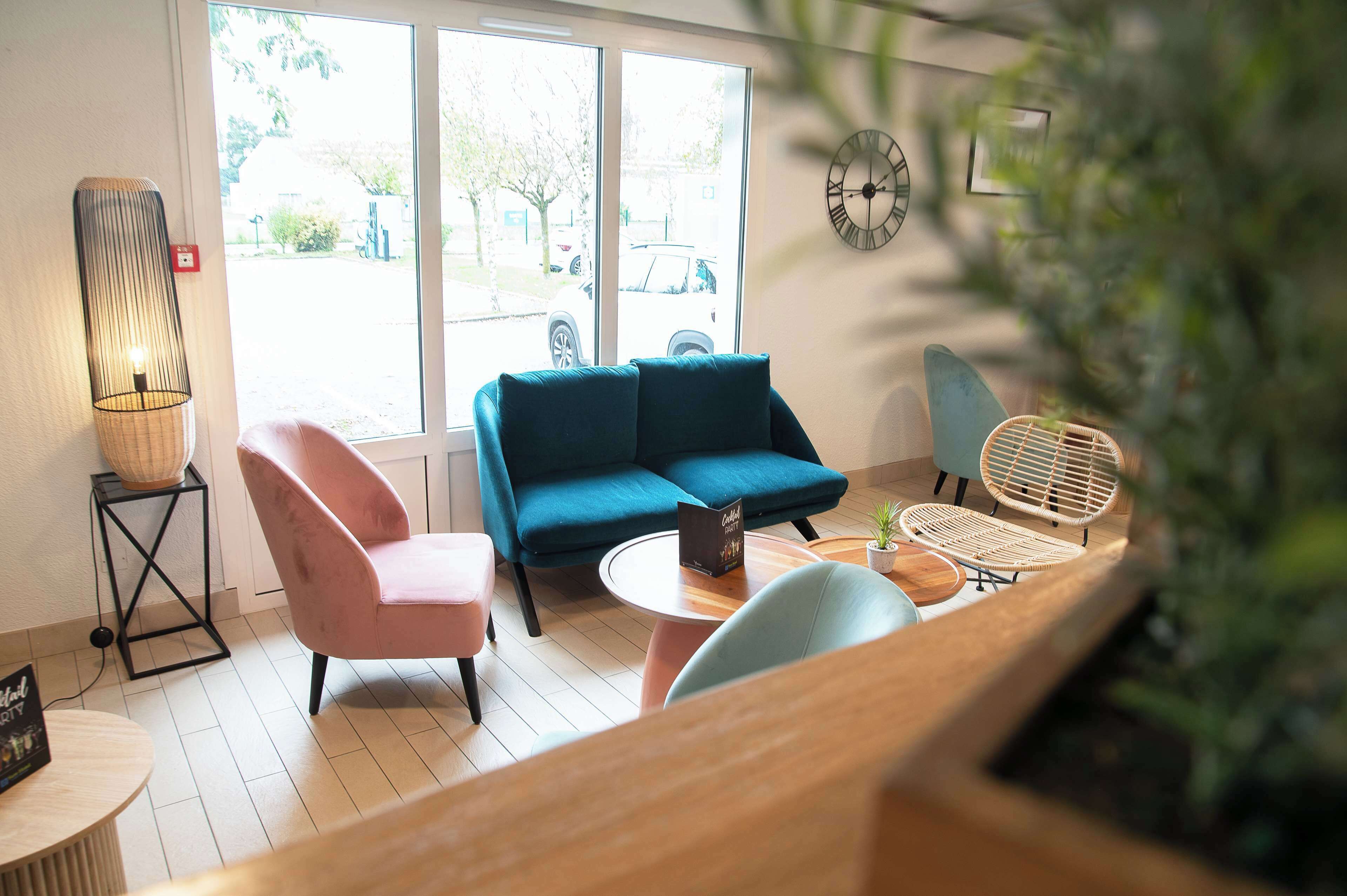 A modern living room with a blue sofa, a pink chair, and a round coffee table.