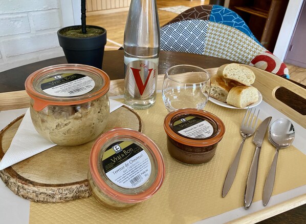 Una mesa de madera con alimentos, un vaso de agua y cubiertos.
