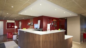 A modern reception area with a wooden counter, a computer, and a red seating area. - Hotel Campanile Bourges Nord- Saint Doulchard (Saint-Doulchard)